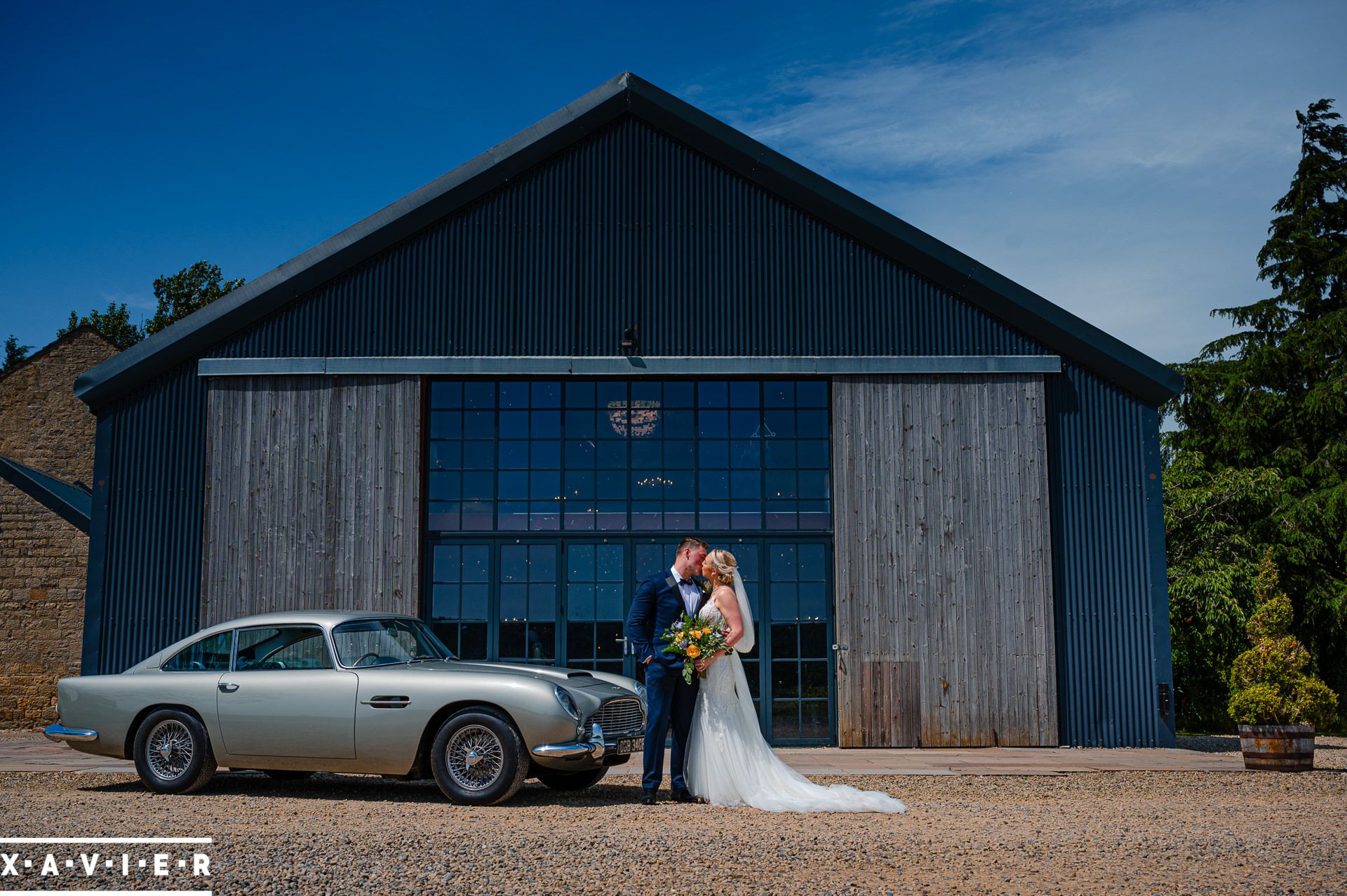 bride and groom kiss by wedding car