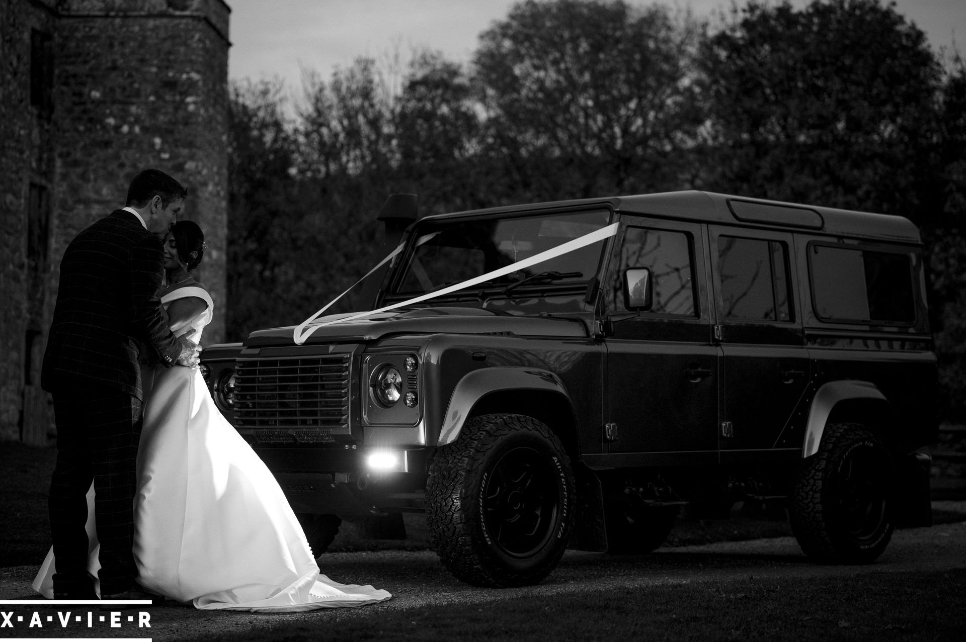 bride and groom stand in front of wedding land rover