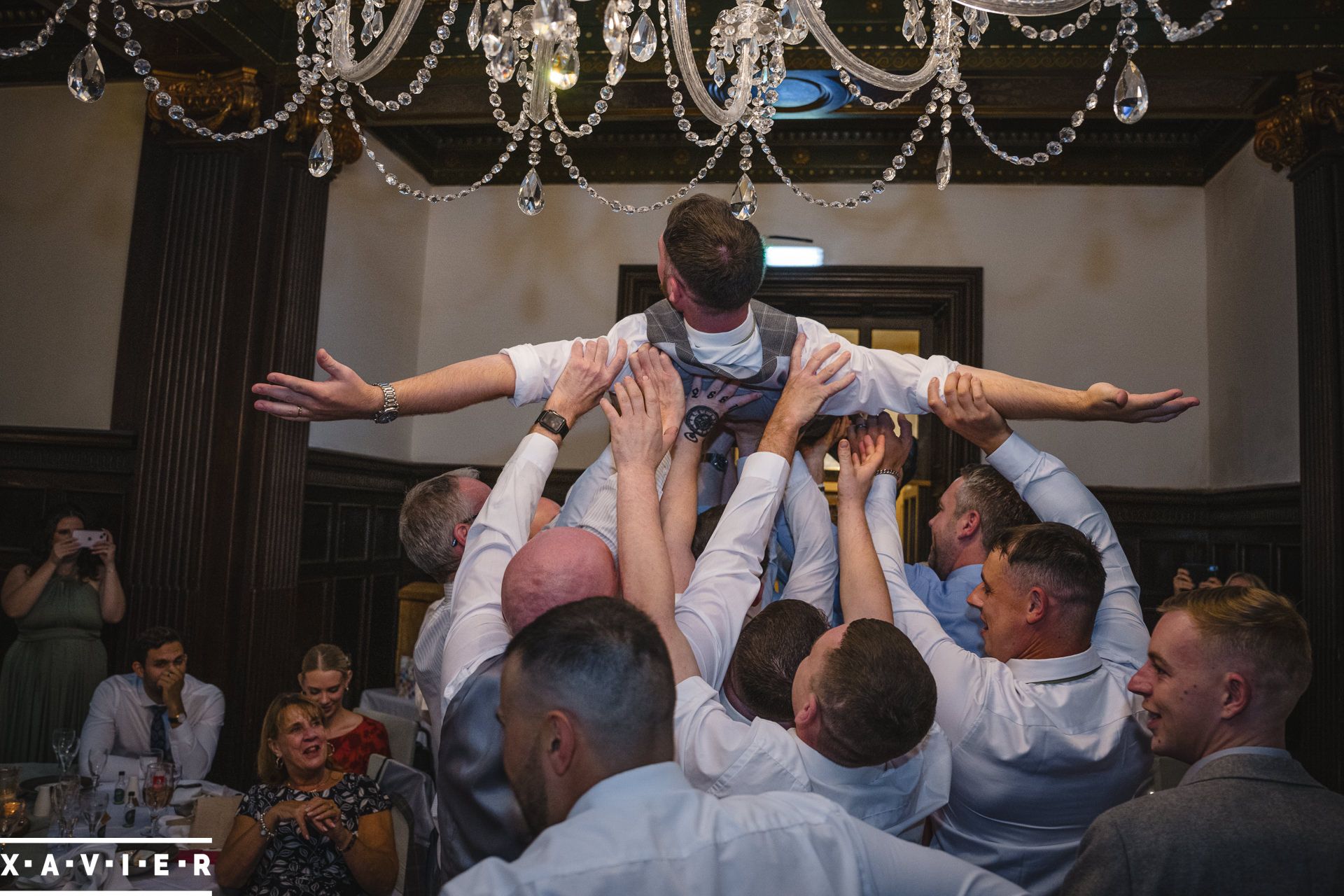 groomsmen hold groom in the air