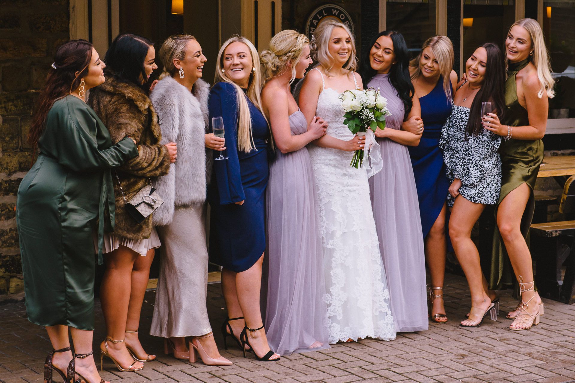 bride and bridesmaids are looking at each other and laughing