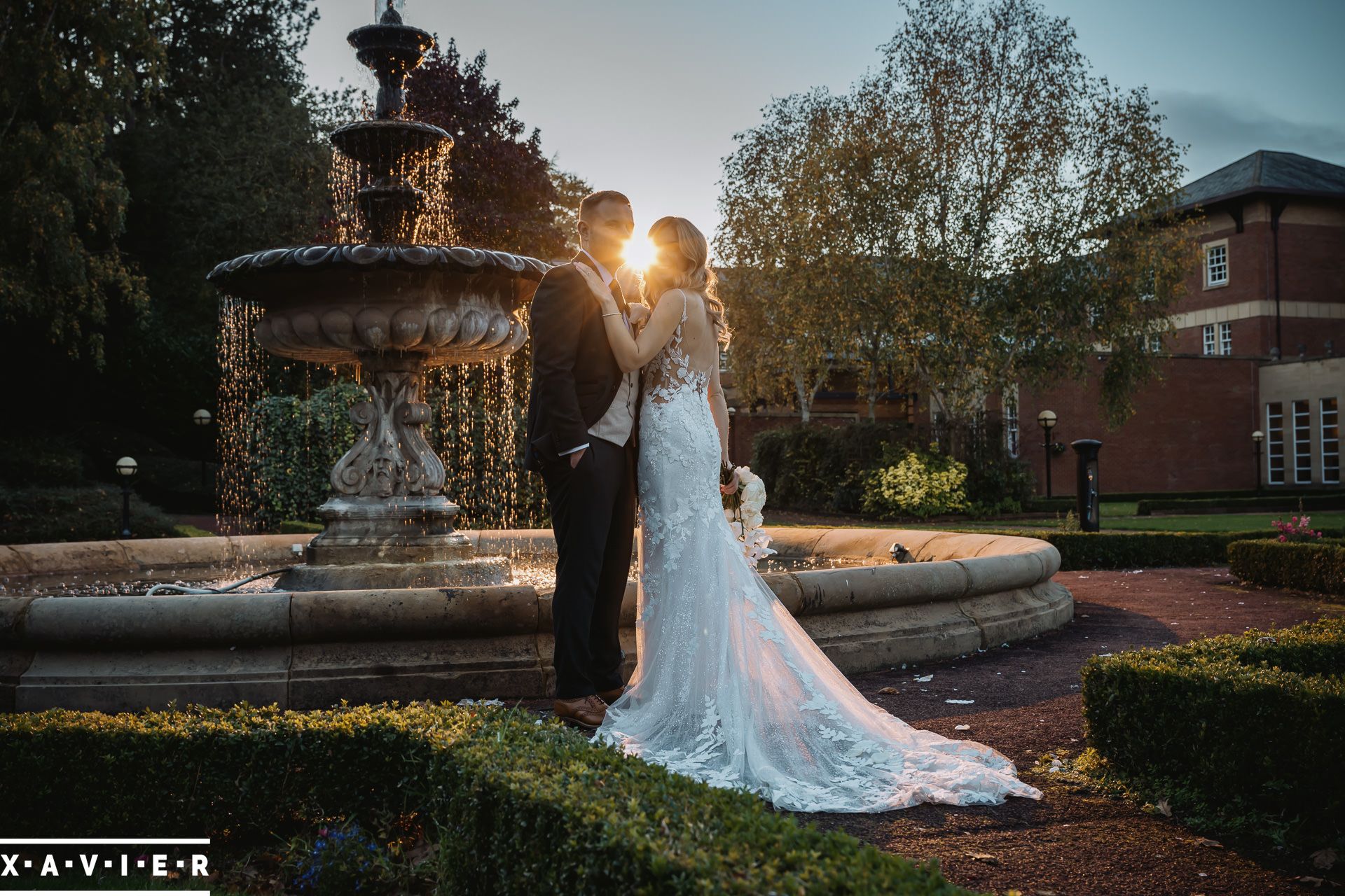 bride and groom by the fountain at sunset