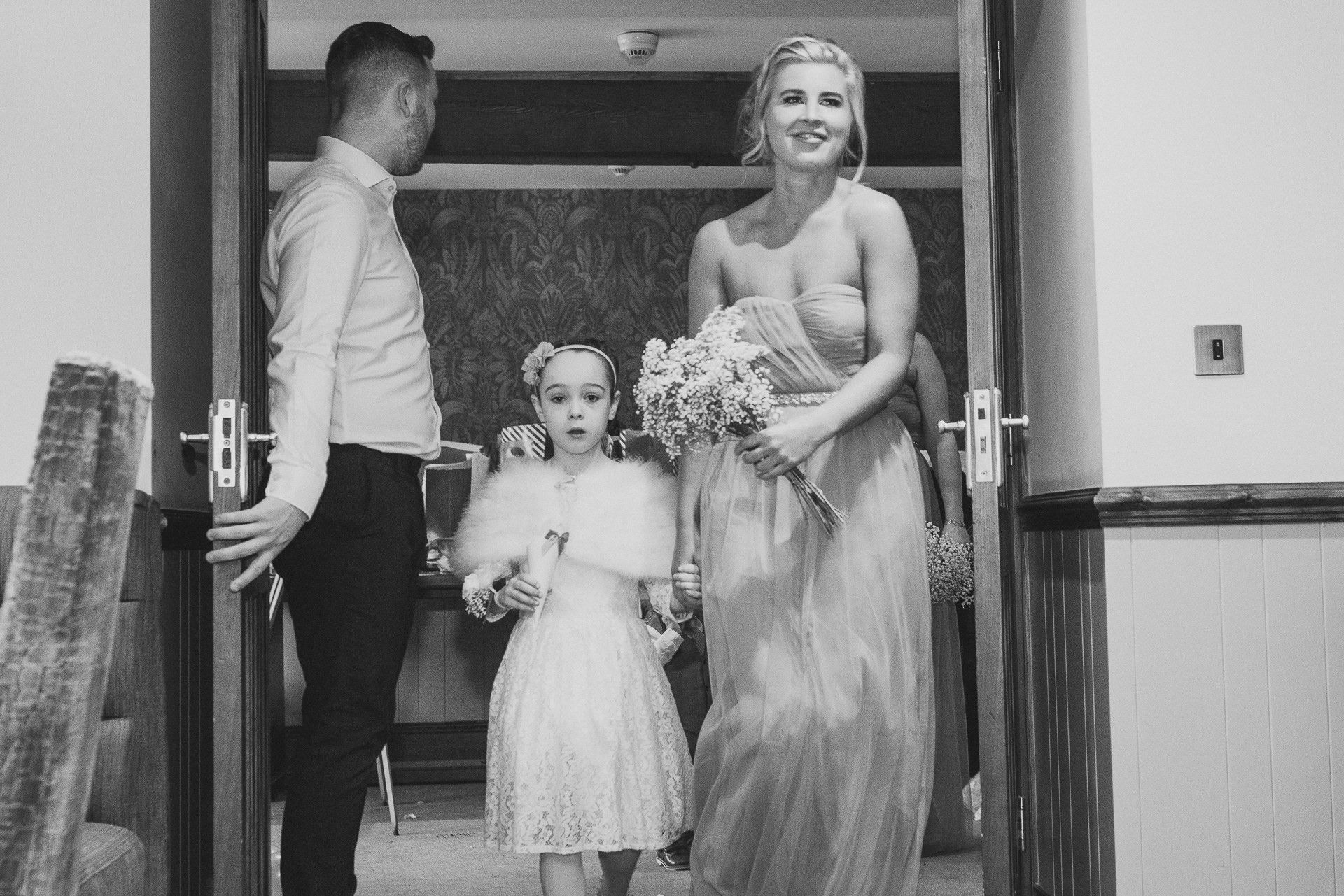 flowergirl looks nervous as she is about to walk down the aisle with a bridesmaid