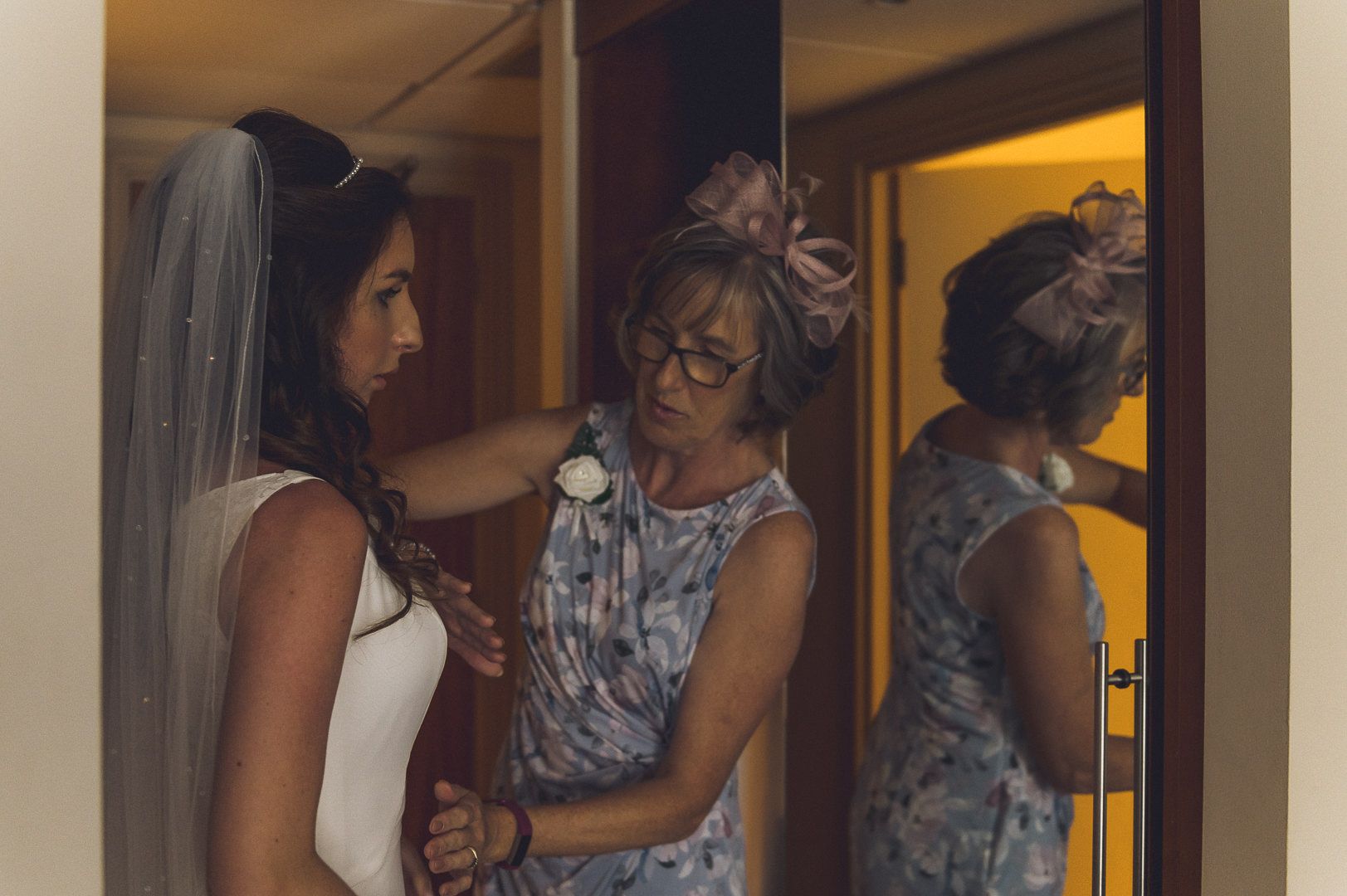 The mother of the bride is helping the bride fit into her dress