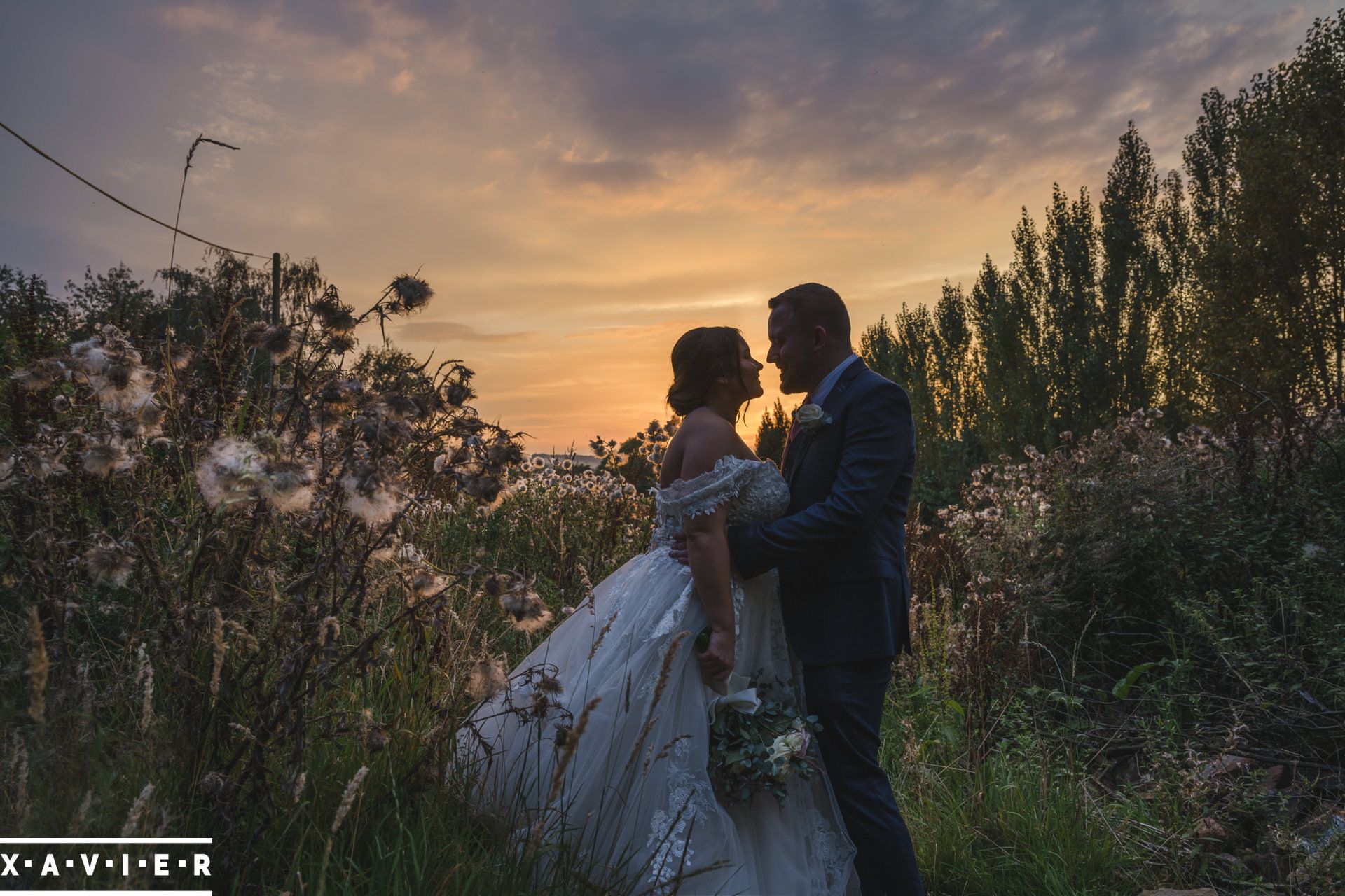 Bride and groom stand togther in the sunset