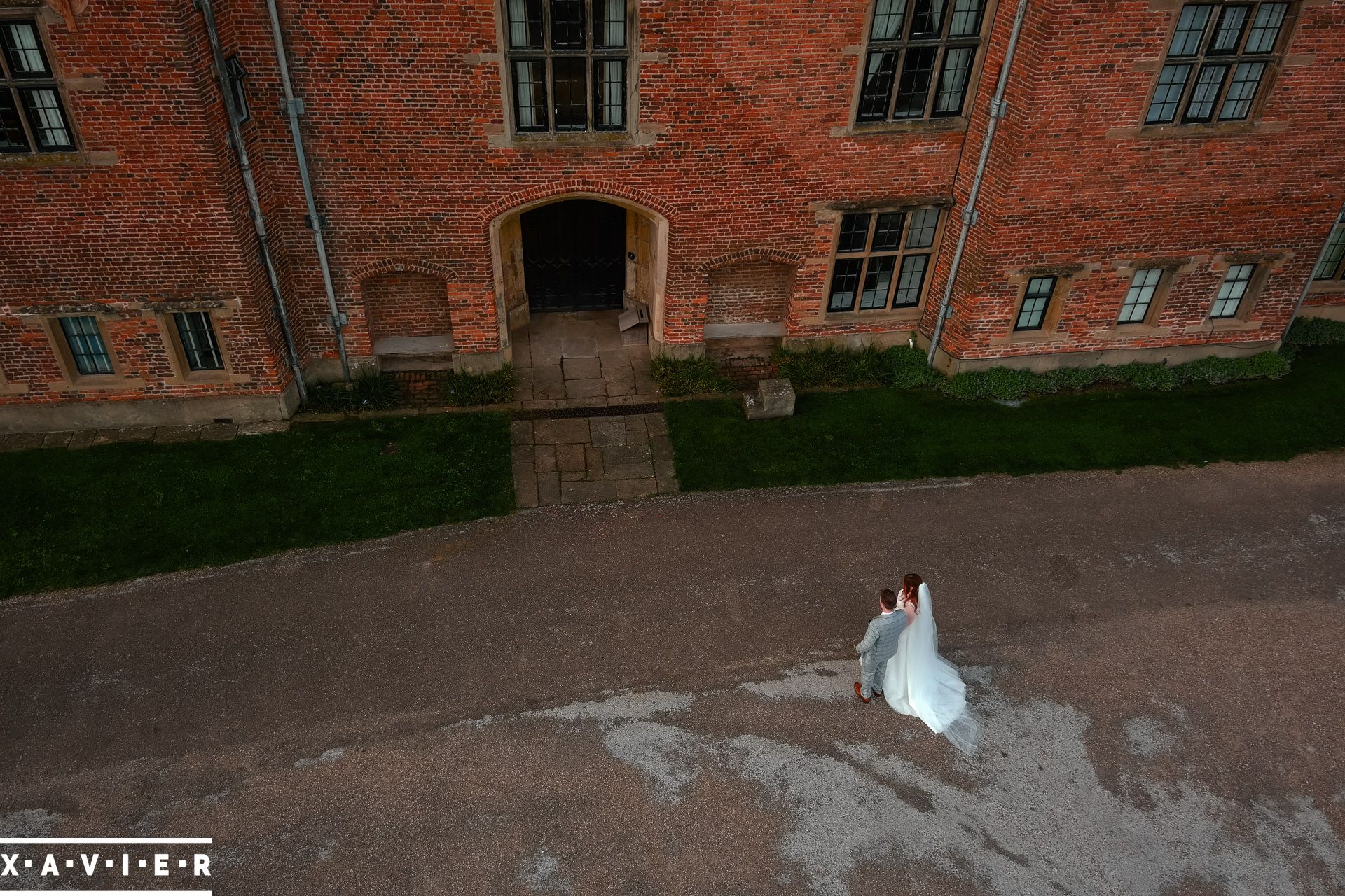 Drone photo of bride and groom walking towards Holme Pierrepont Hall