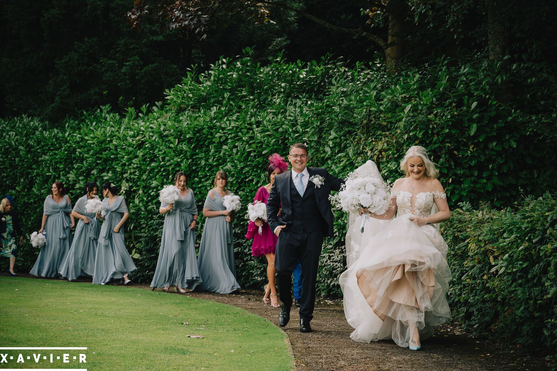 bride and groom walking with bridesmaids behind