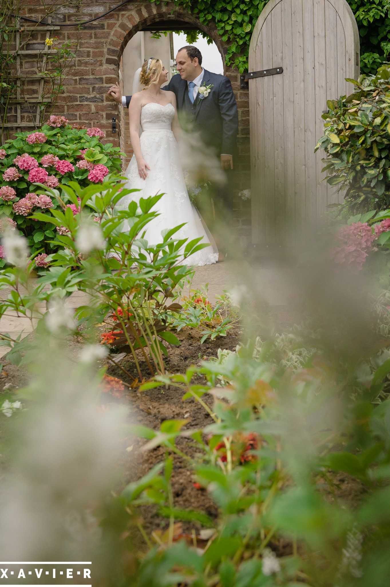 bride and groom stand in the gateway with flowers