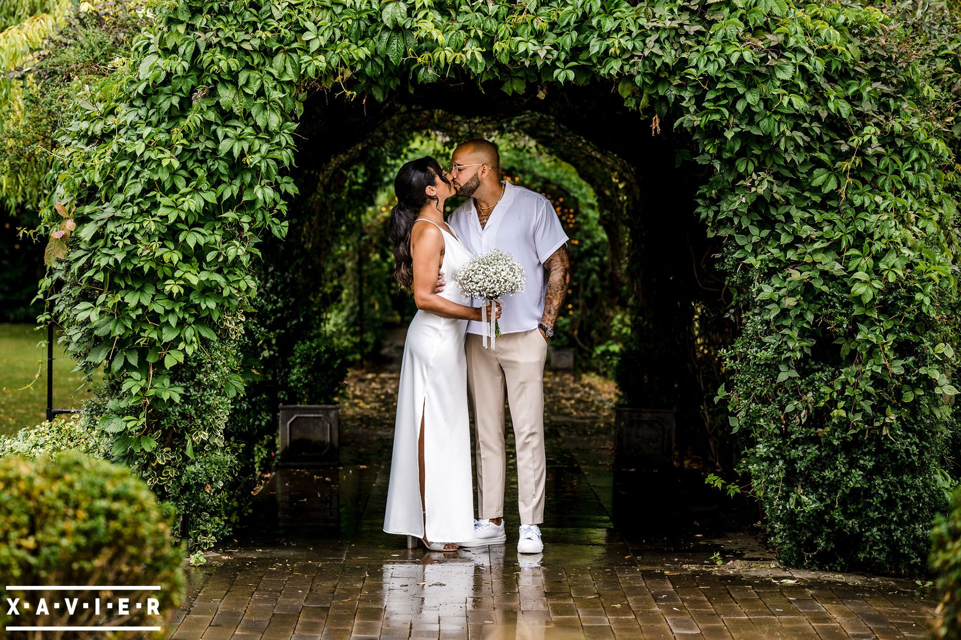 Bridesmaid kisses under archway