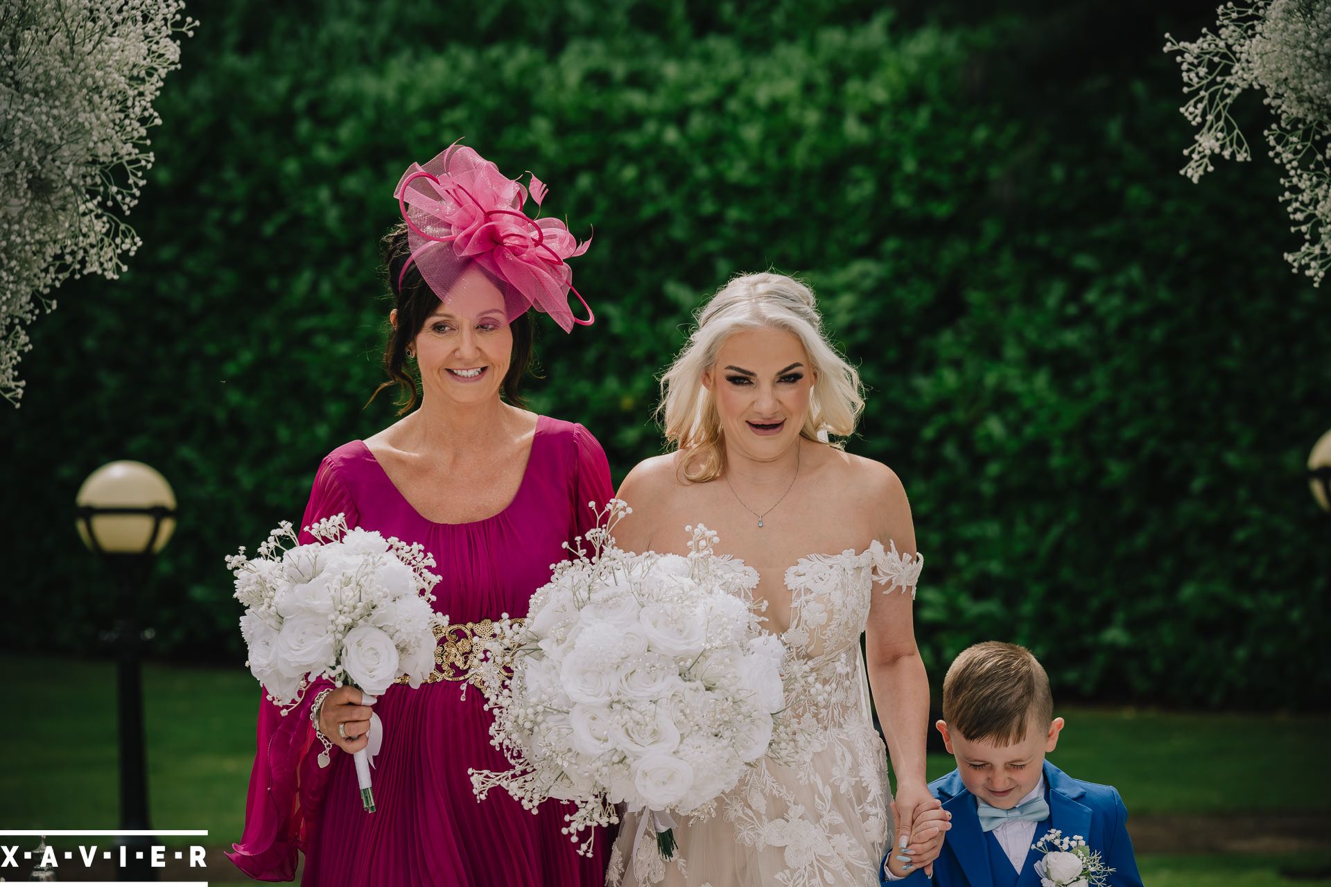 bride walks up the aisle with mother of the bride and pageboy