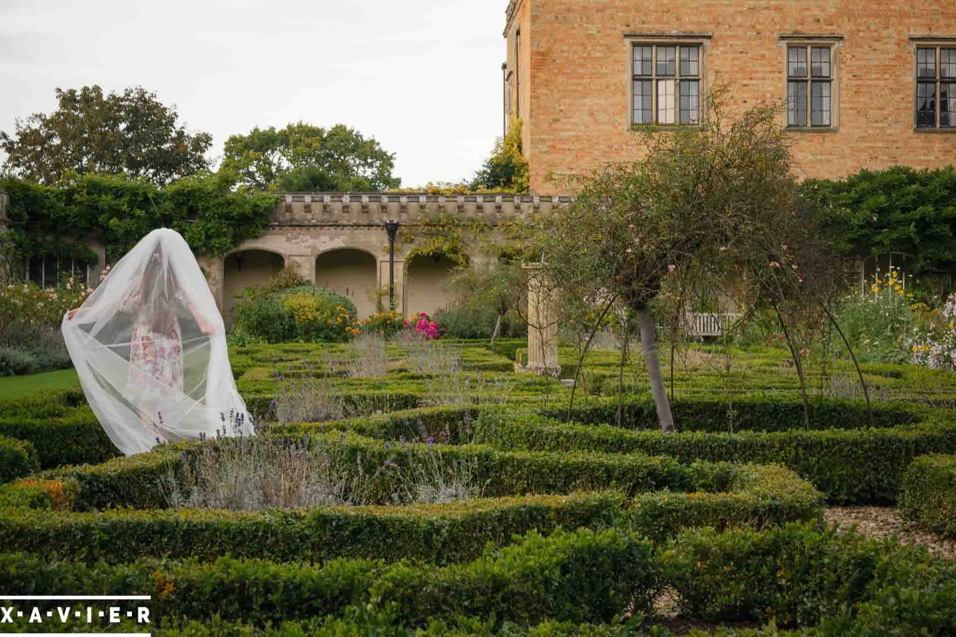 flowergirl walks around the courtyard wearing the brides veil