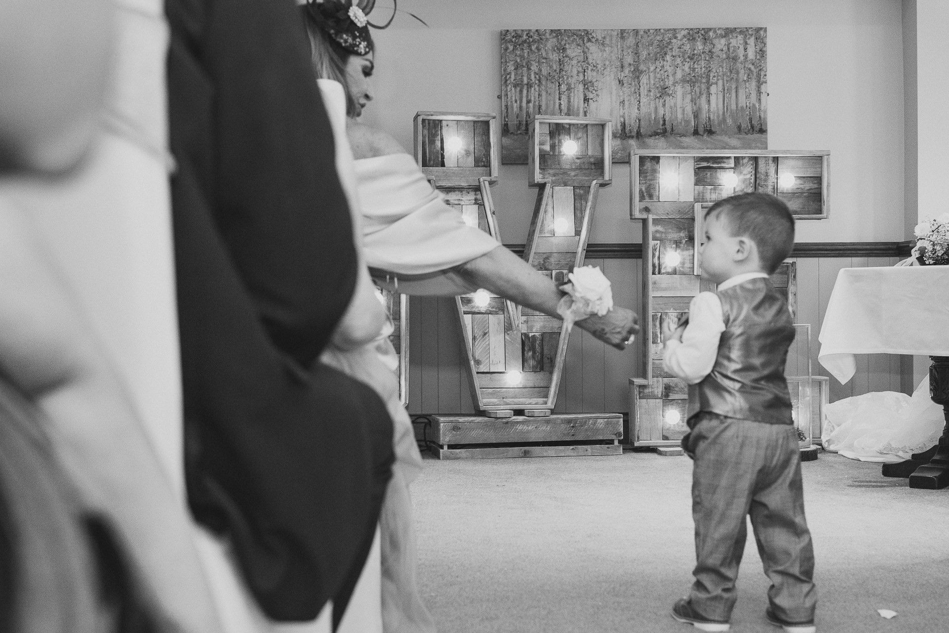 black and white photo of pageboy in the middle of the ceremony aisle