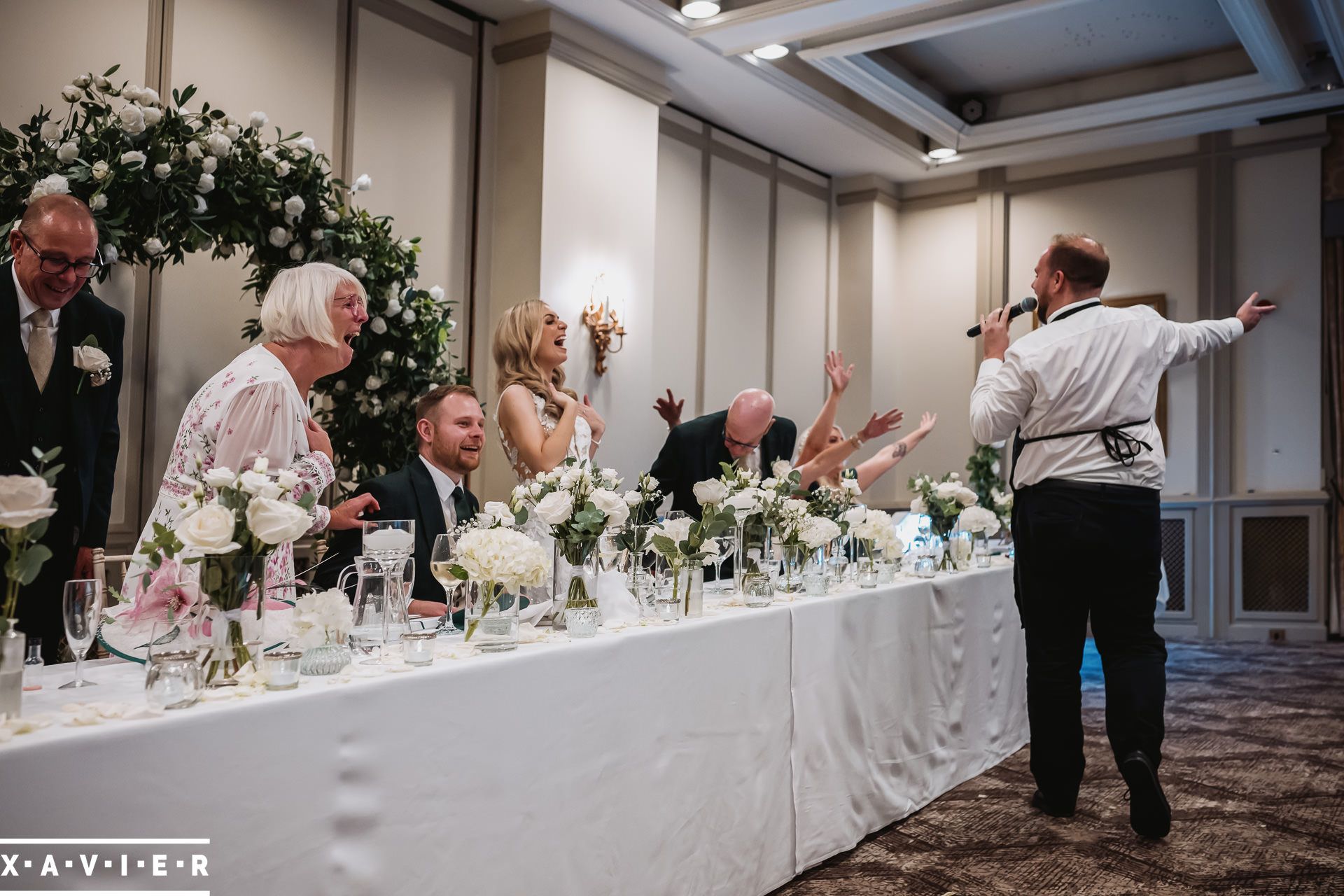 top table guests are suprised at the singing waiter