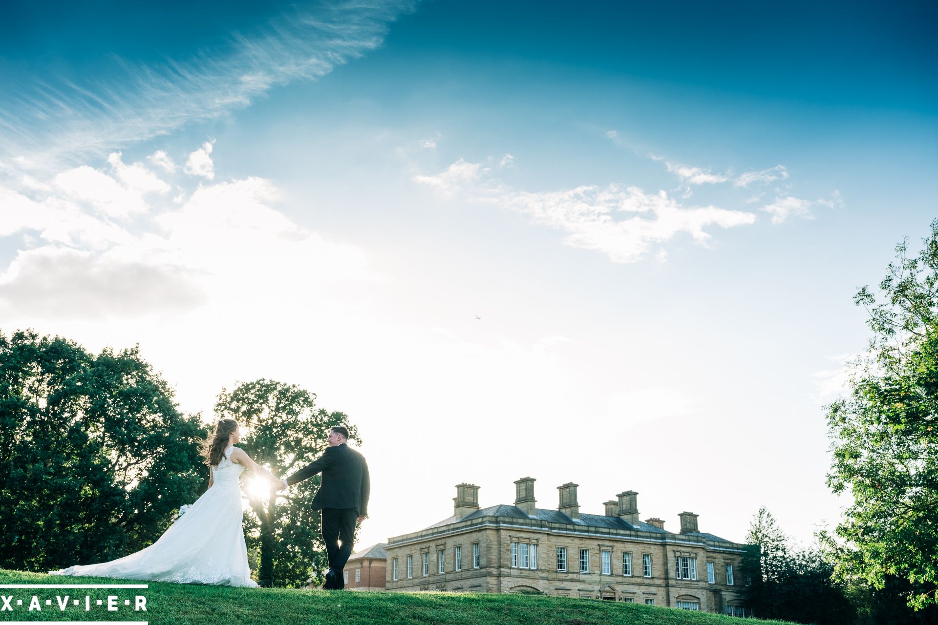 bride and groom walk hand in hand towards Oulton Hall