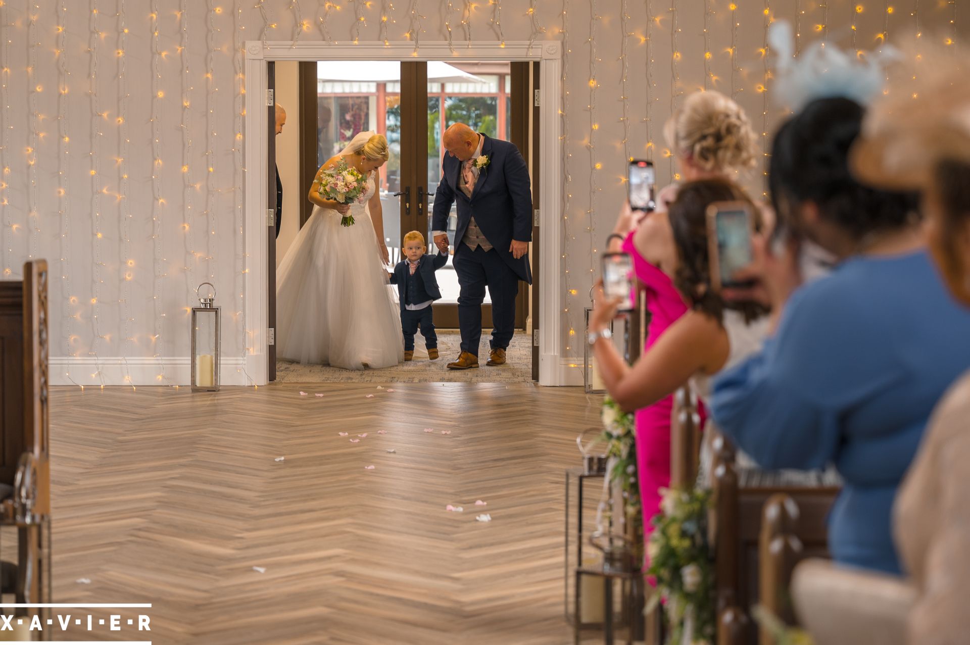 bride walks down the aisle with pageboy and father of the bride