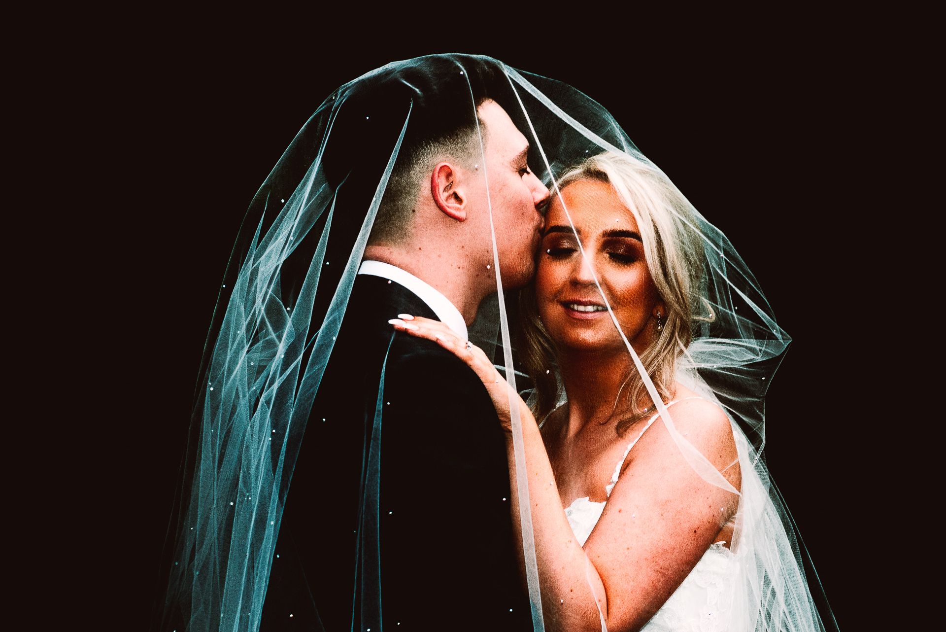 bride closes her eyes as she embraces the groom under her veil