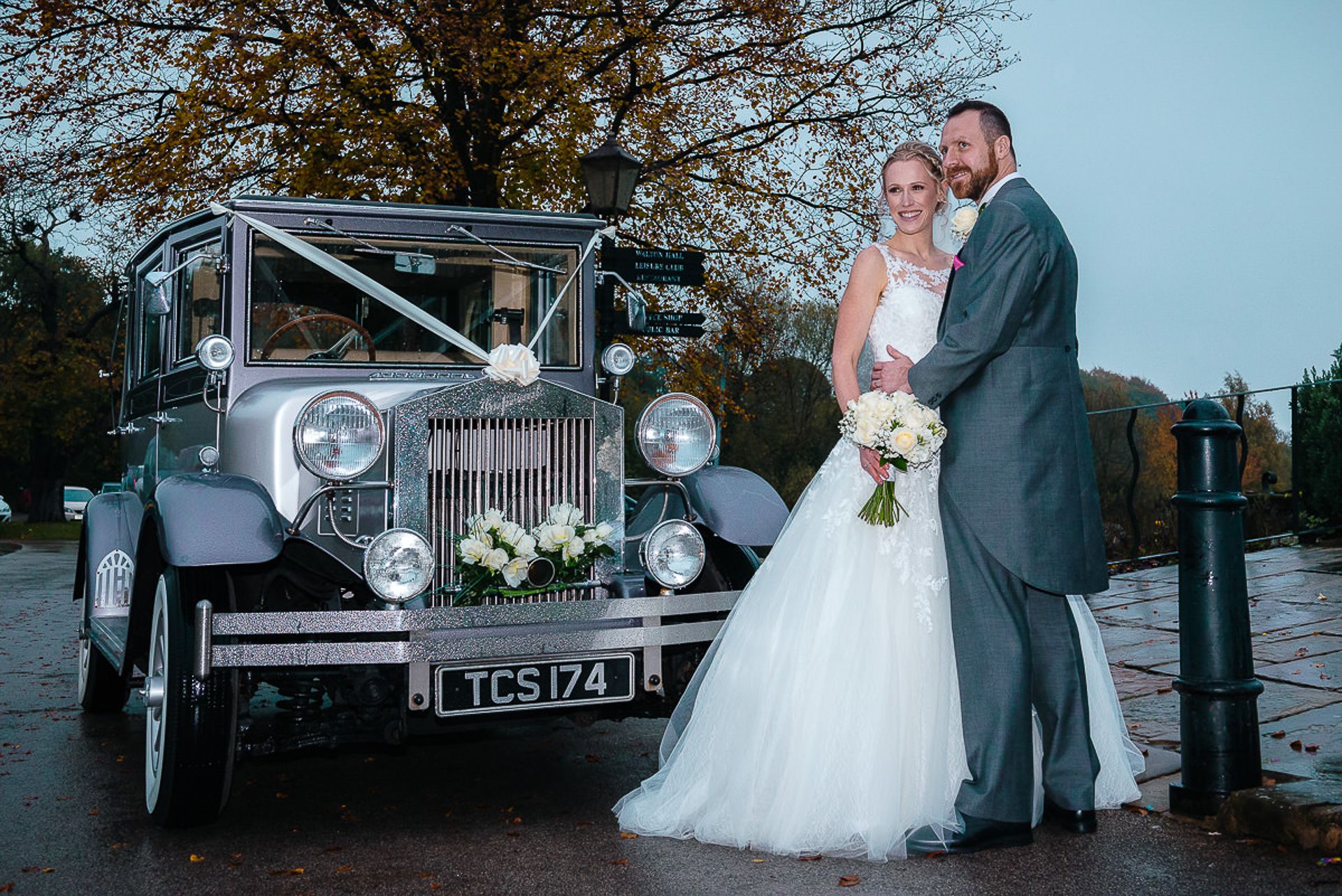 bride and groom pose beside the vintage wedding car