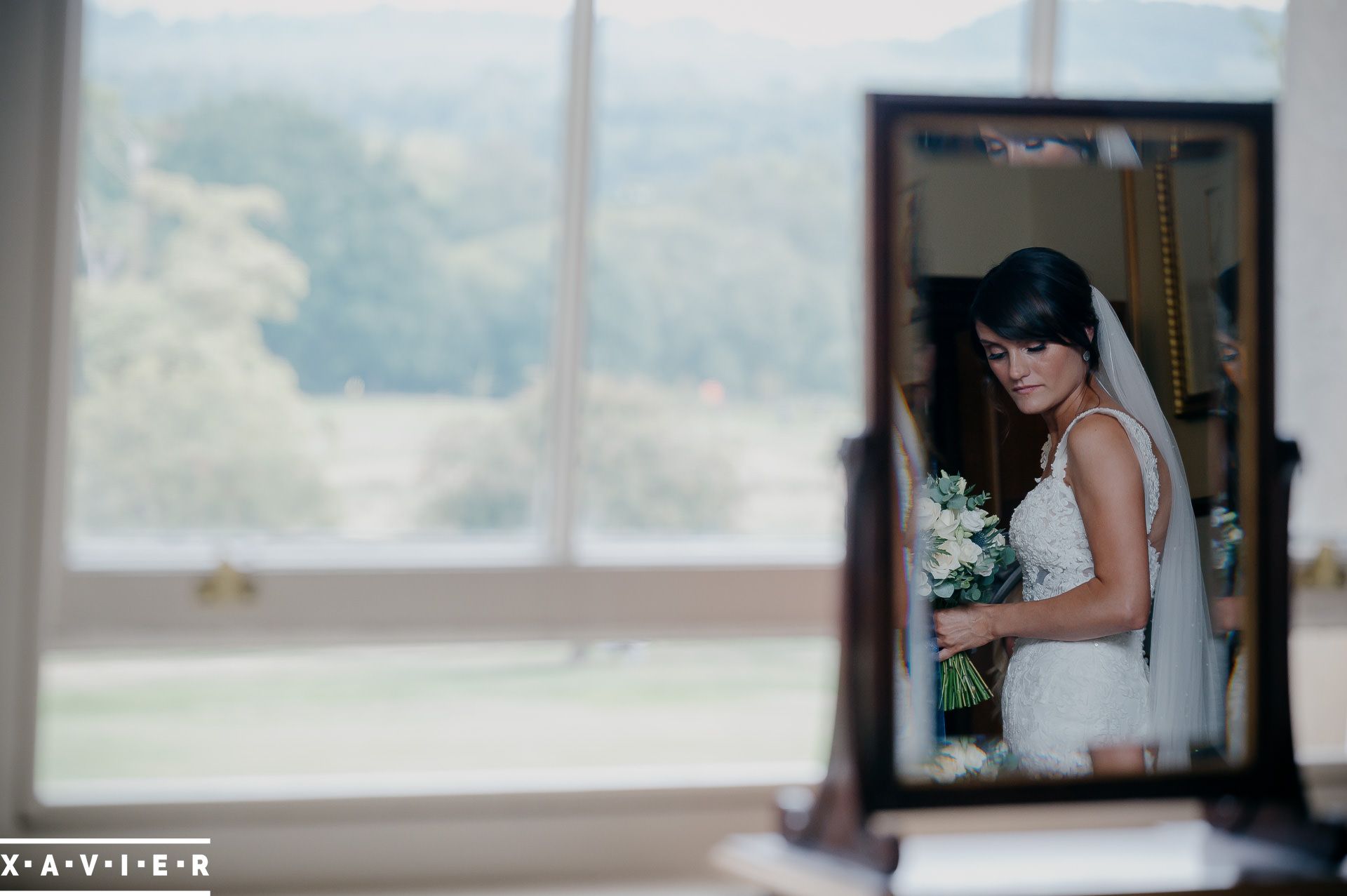 bride seen holding flowers in the mirror